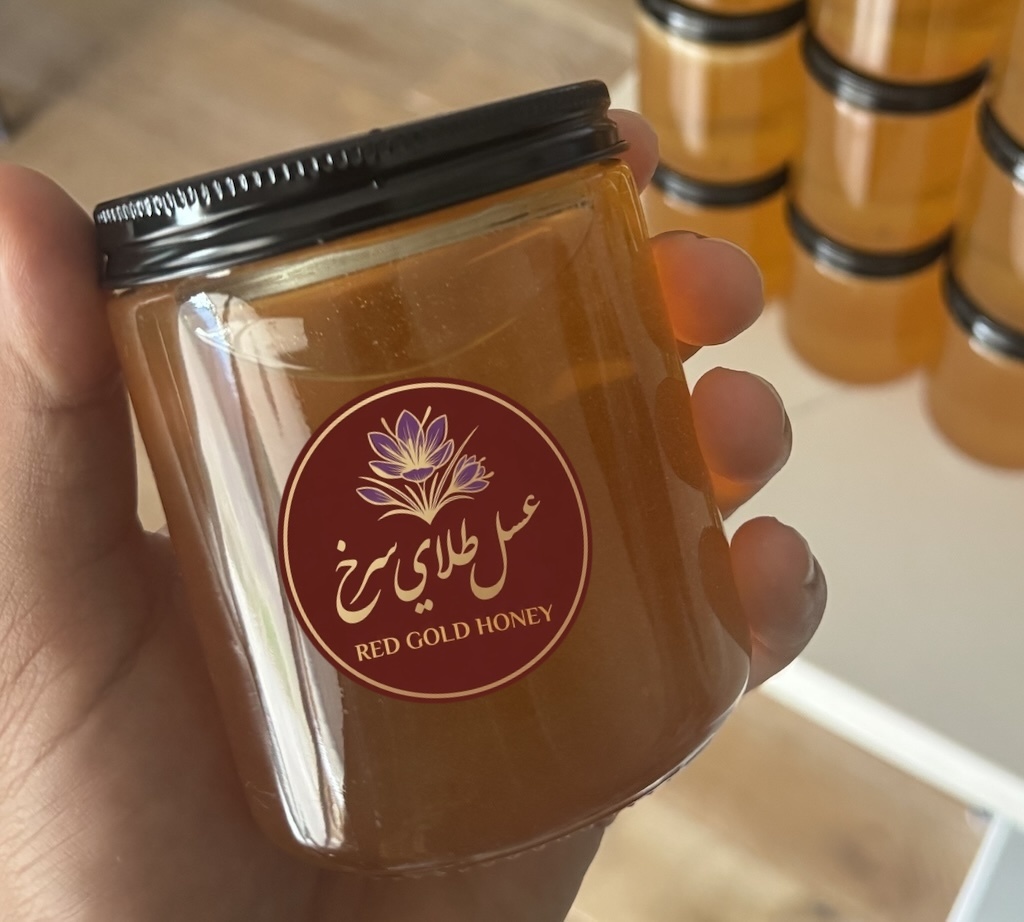 A jar of Red Gold Honey with the Red Gold Honey logo, held in hand